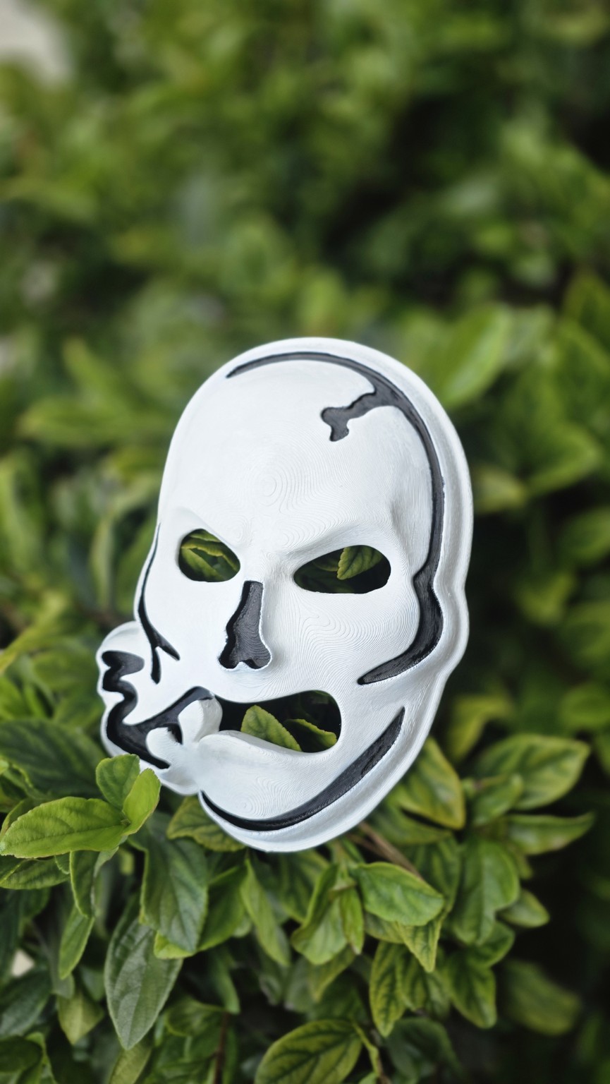 Black and white 3D printed skull decoration displayed in greenery