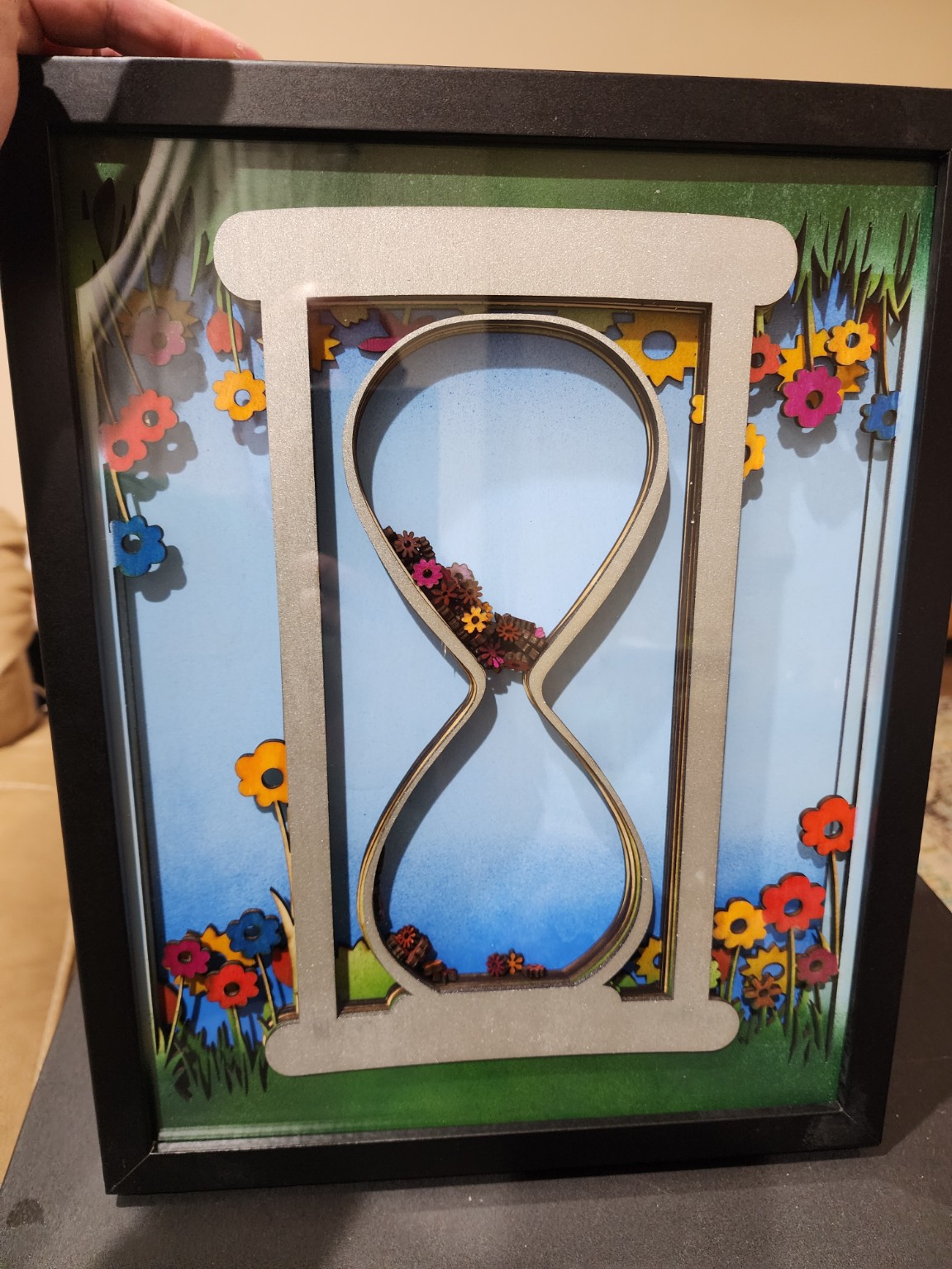 Layered infinity symbol surrounded by colorful flowers in a shadowbox
