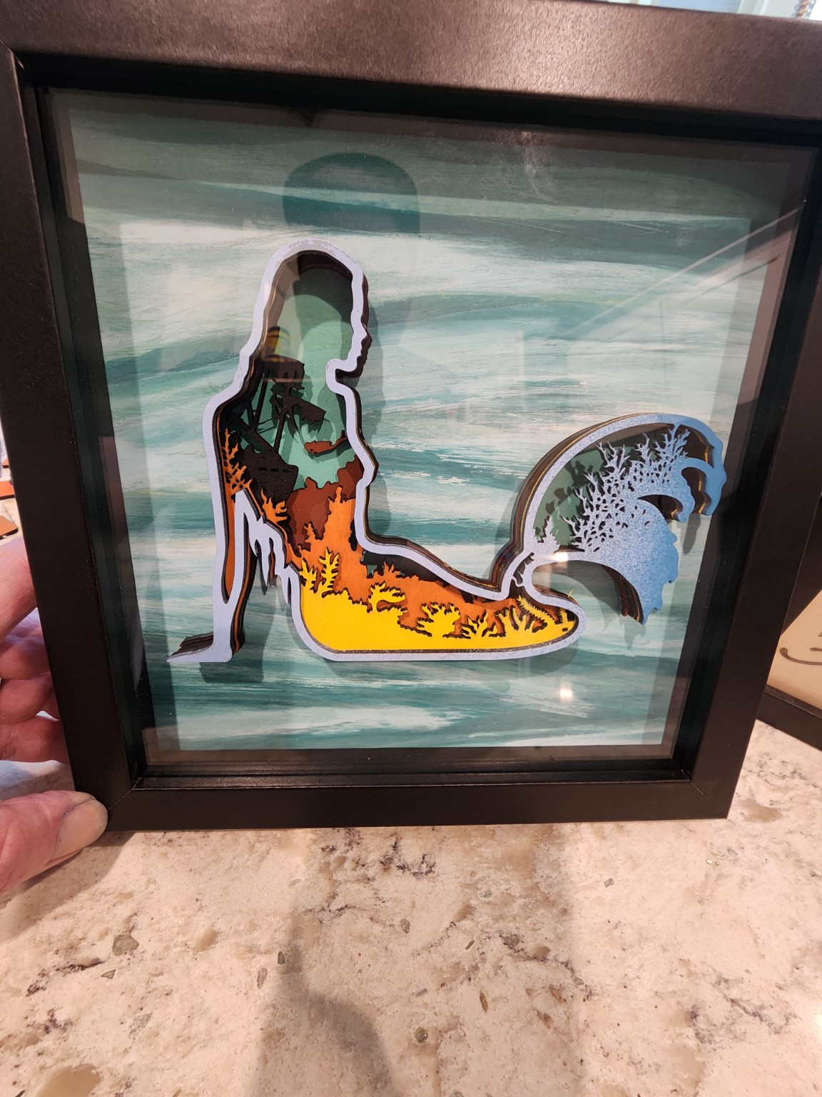 Layered surfer and wave artwork in a black shadowbox